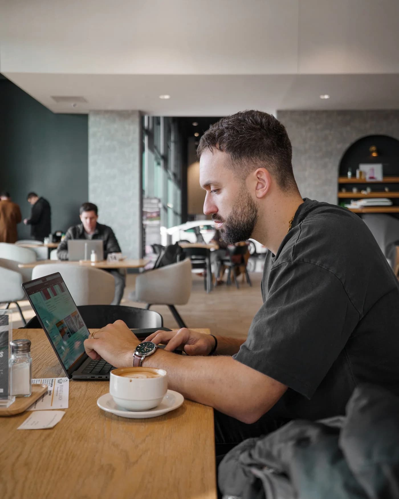 Kyle Hoffman working on a laptop over a cappuccino in a cafe